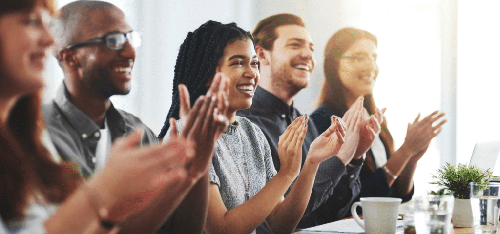 employees sitting at table clapping