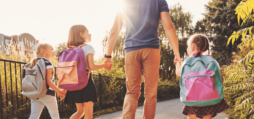 father walking his three schoolchildren to school